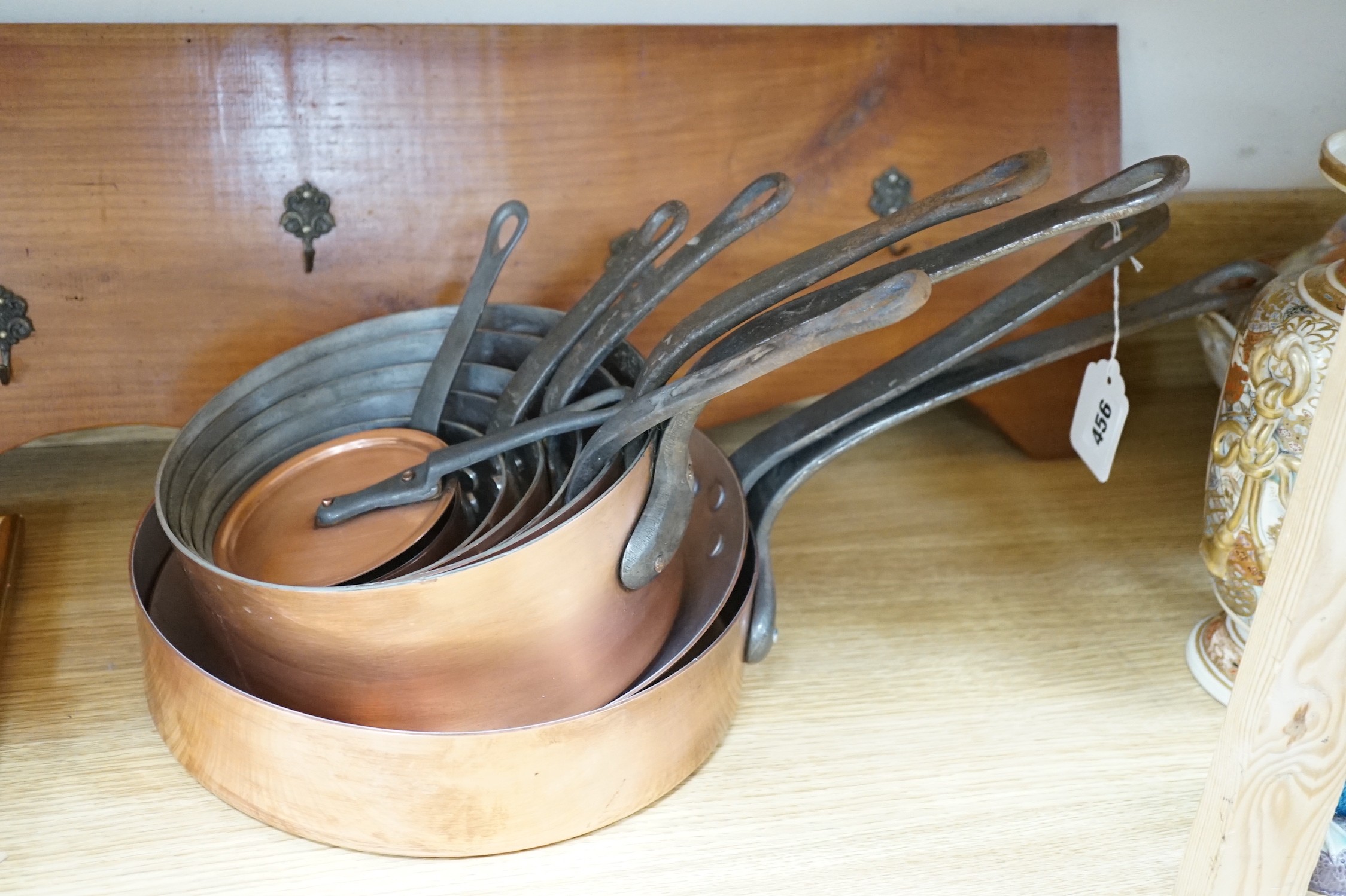 A nine piece graduated copper pan set with rack, unmarked